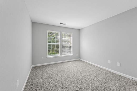 A room with a window and a carpeted floor.